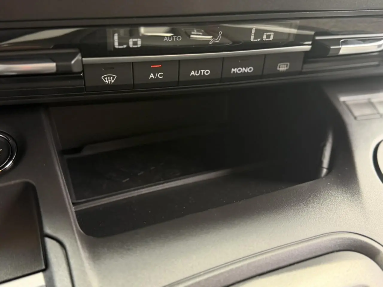 Gros plan sur la console centrale du Peugeot Rifter 2026, montrant les commandes de climatisation automatique et un espace de rangement noir.