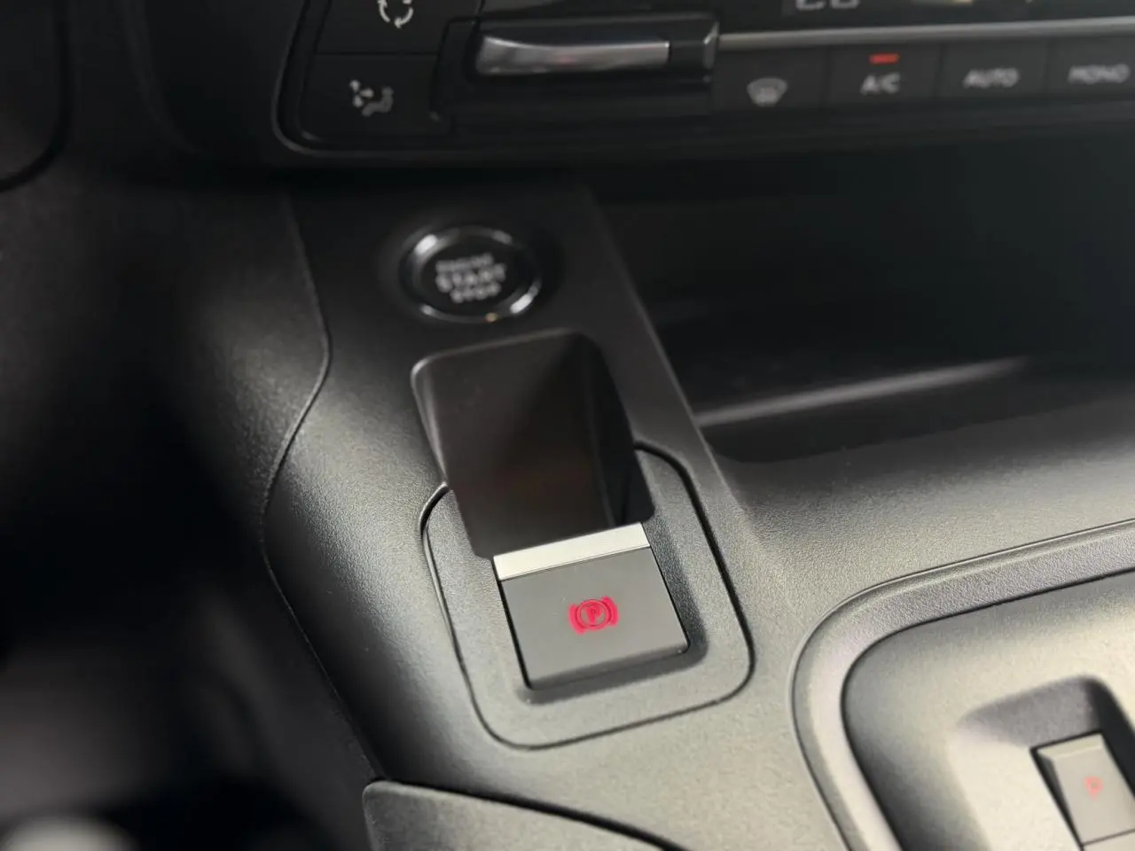Gros plan sur le frein de stationnement électrique et le bouton start/stop dans l’habitacle noir du Peugeot Rifter 2026.