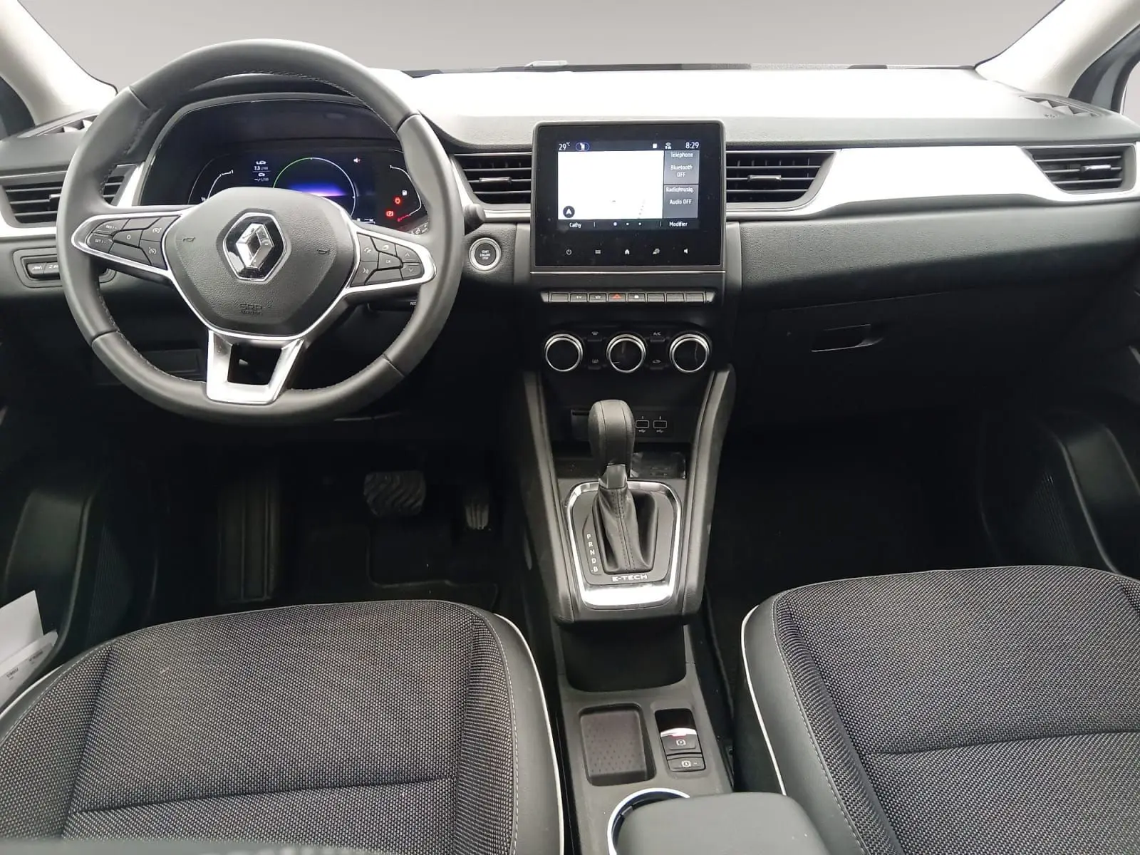 Vue intérieure frontale du tableau de bord du Renault Captur E-Tech hybride, avec écran tactile et volant multifonction.