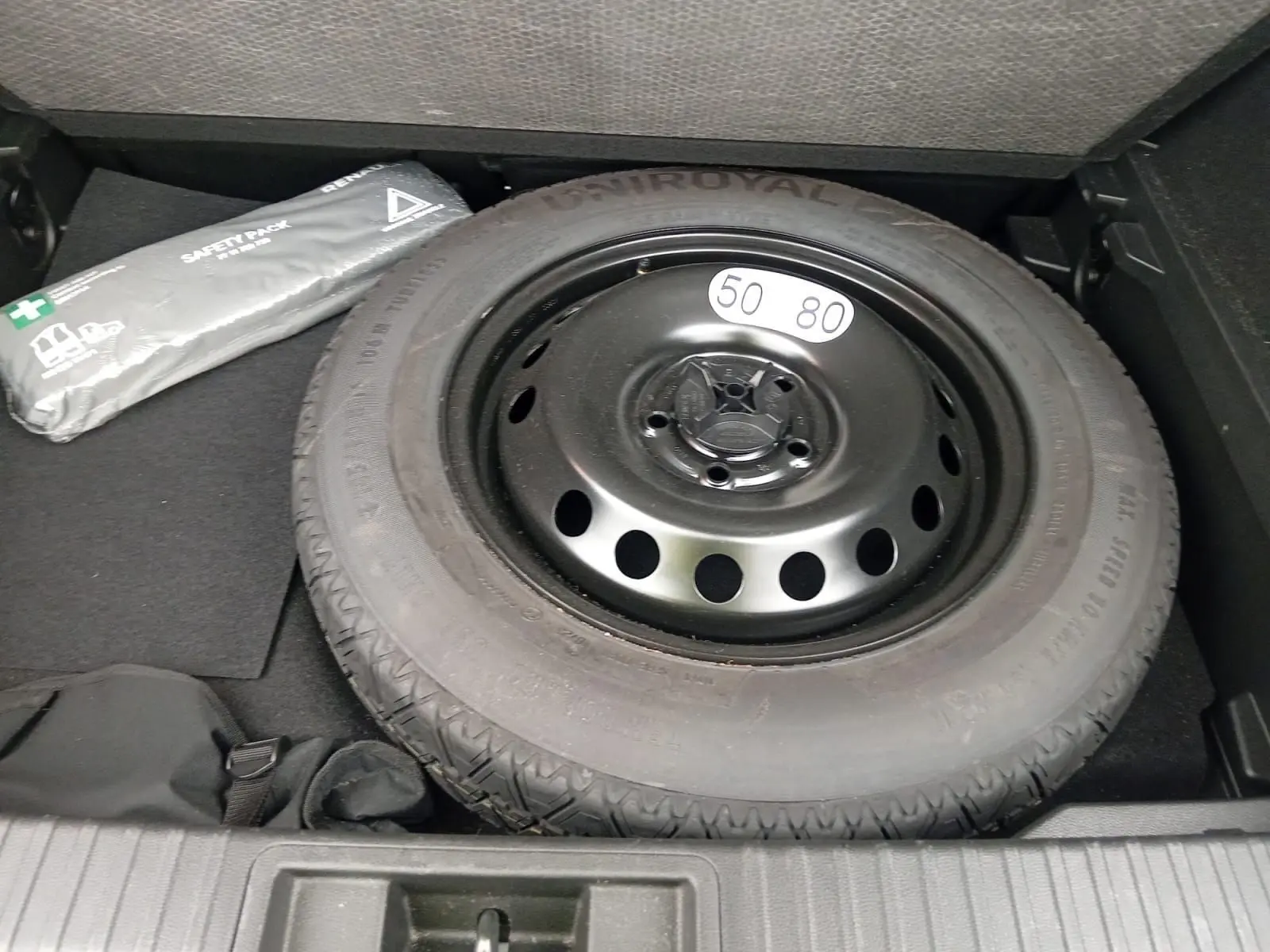 Pneu de secours noir avec étiquette 50-80 dans le coffre d'un Renault Captur gris alu/noir 2023.