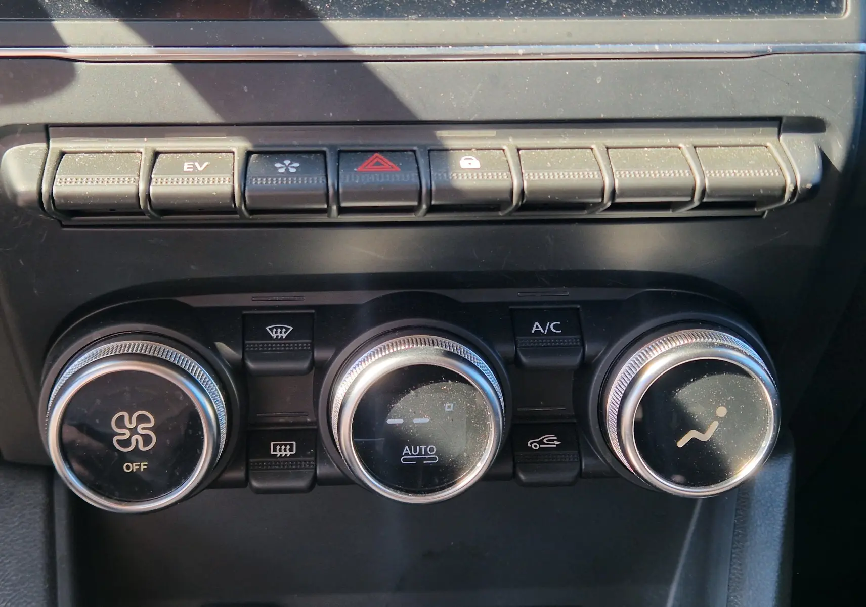 Gros plan sur les commandes de climatisation et boutons de fonction du tableau de bord du Renault Captur gris alu/noir 2023.