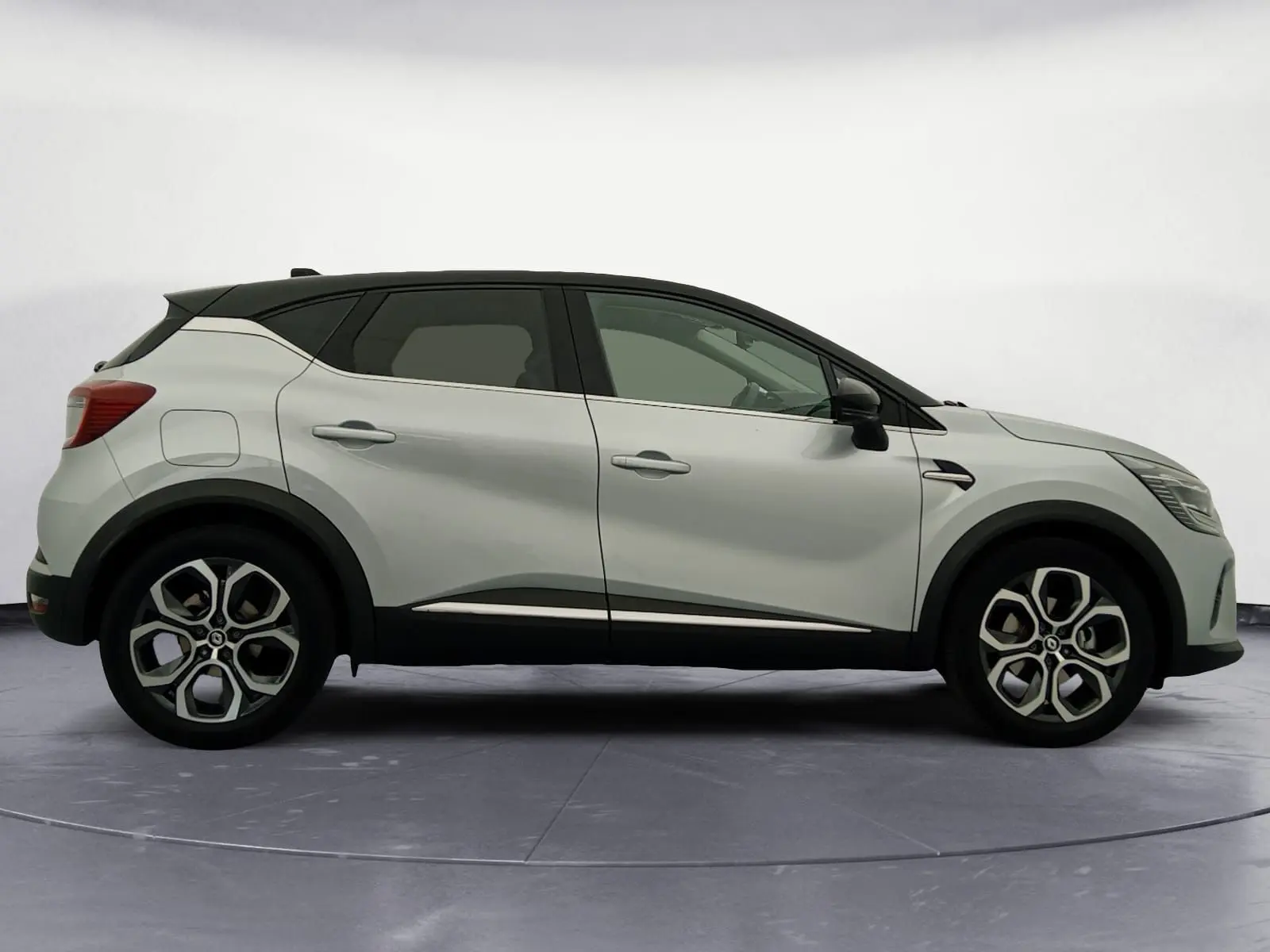 Profil droit du Renault Captur 2023 hybride gris alu avec toit noir et jantes alliage 18 pouces distinctives.