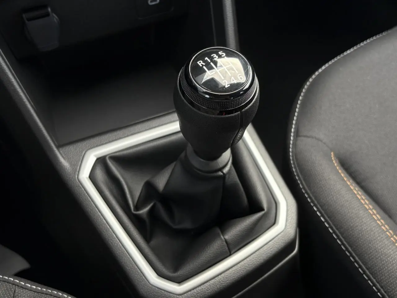 Gros plan sur le levier de vitesses manuel noir de la Dacia Sandero Stepway 2025, avec coutures apparentes sur la sellerie grise.