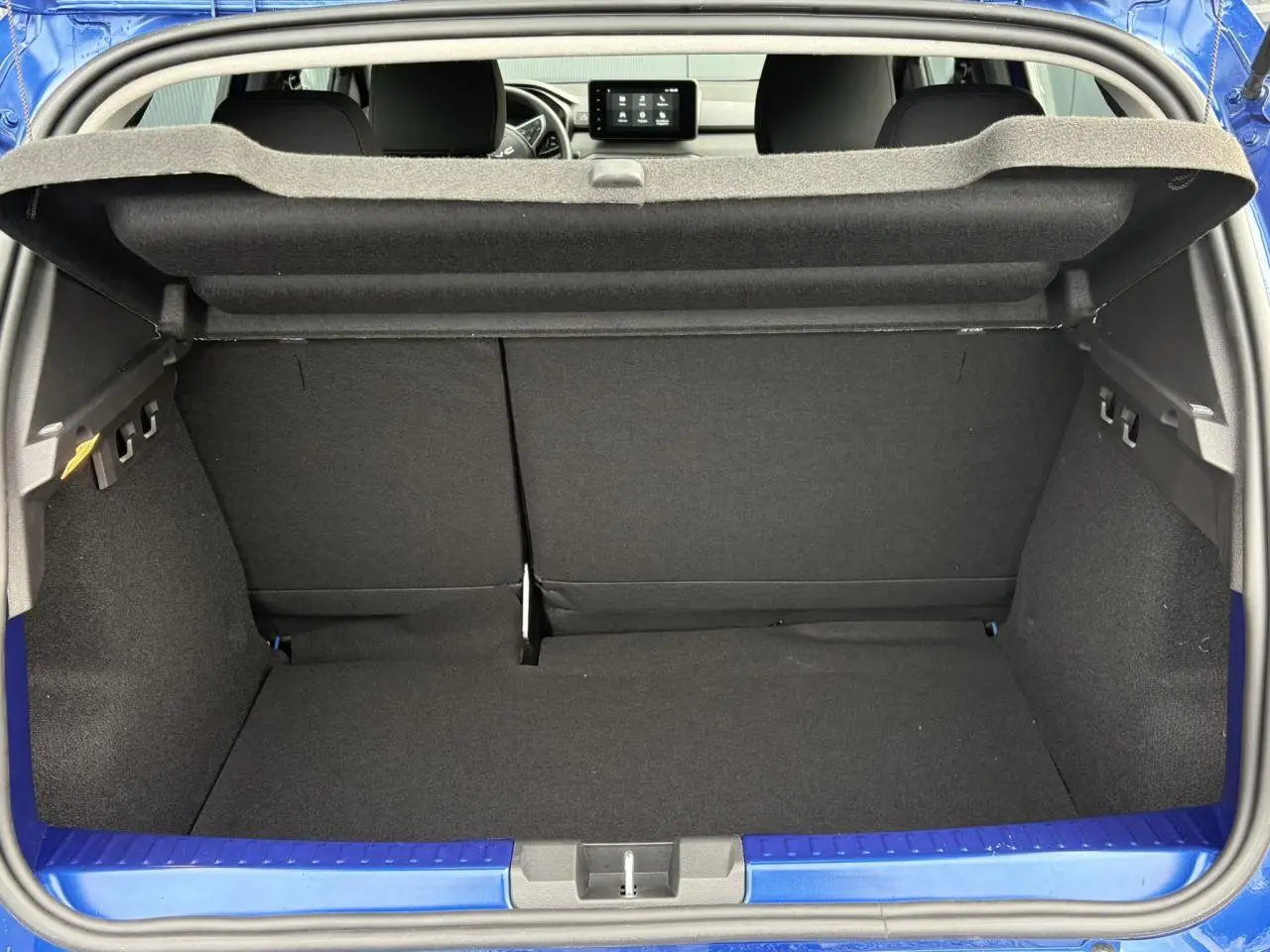Coffre ouvert d'une Dacia Sandero Stepway bleu Iron, vue arrière montrant l'espace de chargement et l'intérieur noir.