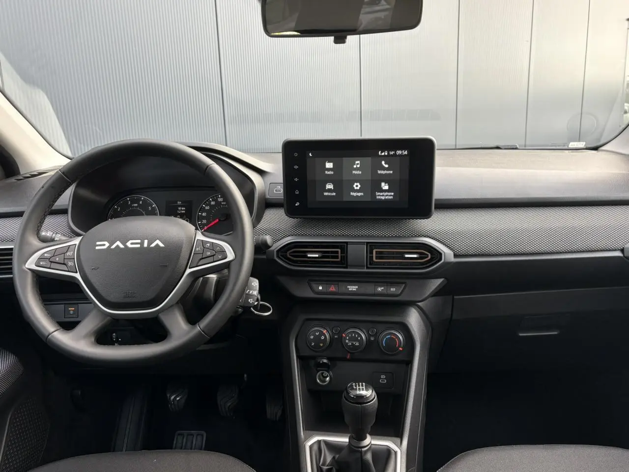 Vue intérieure frontale du tableau de bord et volant noir de la Dacia Sandero Stepway 2025 avec écran tactile central.