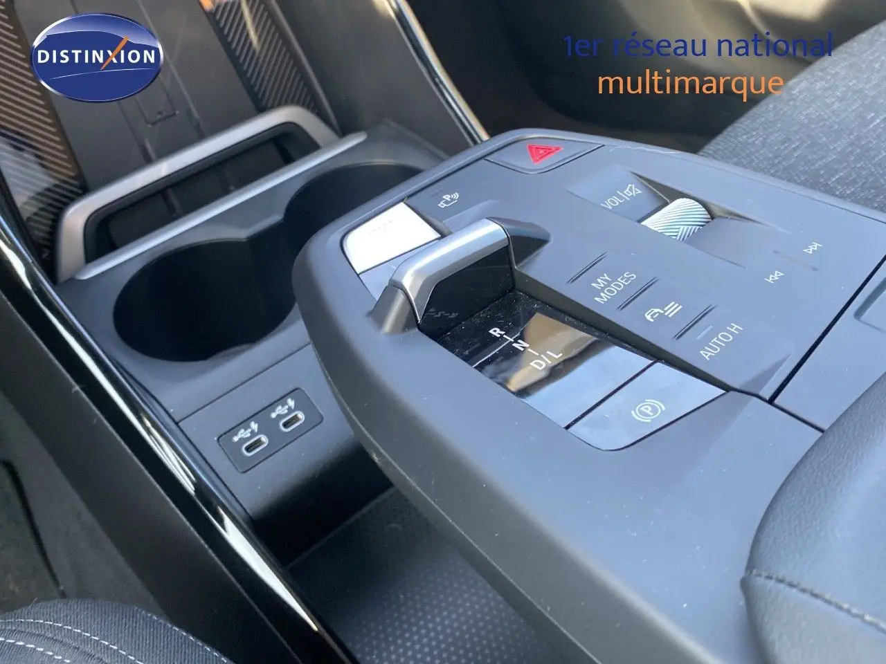 Gros plan sur la console centrale avec levier de vitesses et commandes du BMW X1 18I bleu Phytonic 2024.