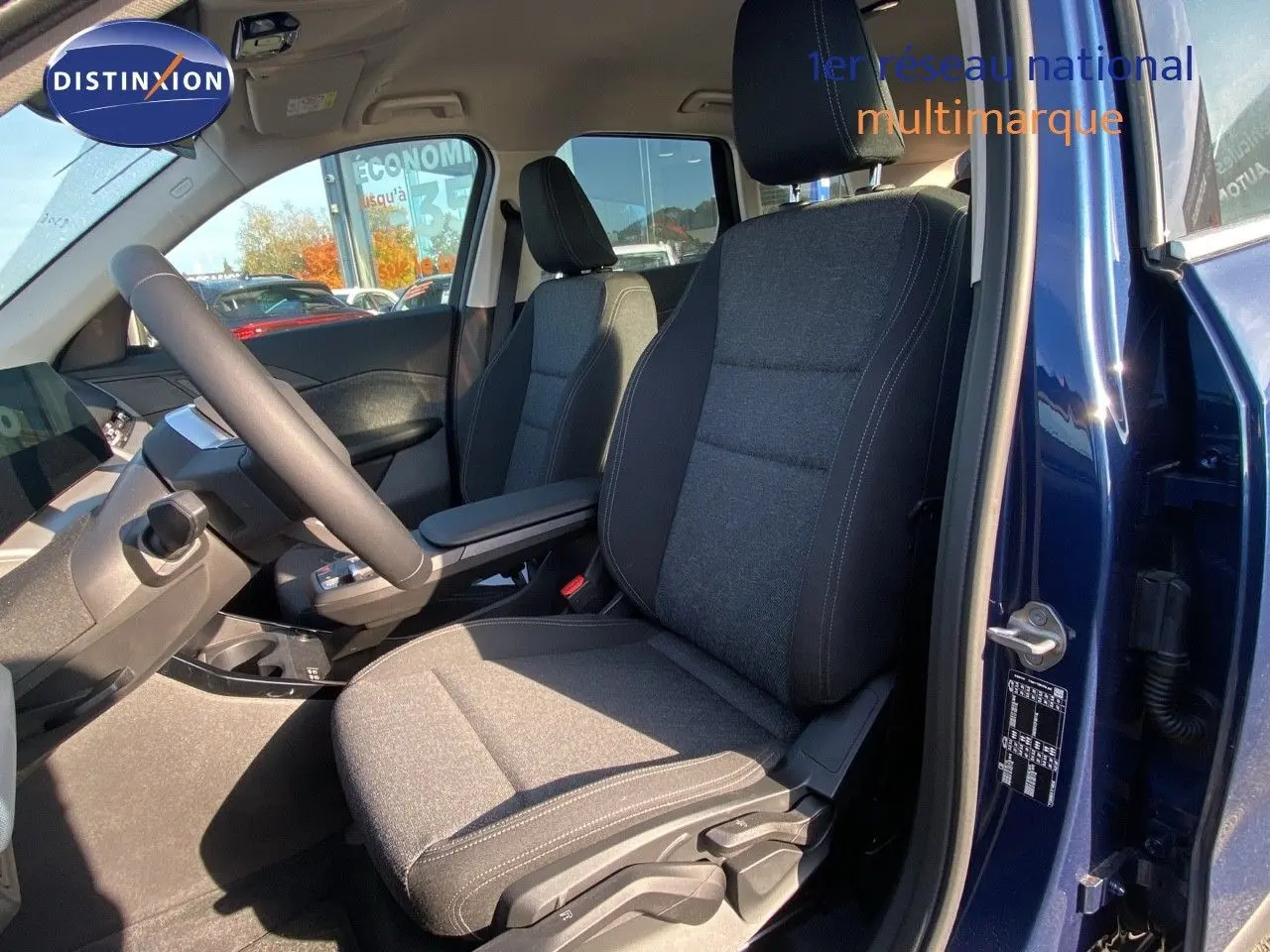 Vue intérieure côté conducteur du BMW X1 18I bleu Phytonic avec sièges tissu gris et tableau de bord moderne.