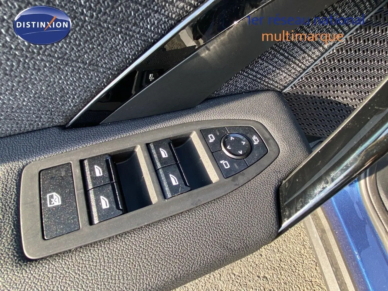 Gros plan sur les commandes des vitres et rétroviseurs côté gauche d'un BMW X1 bleu phytonic metal 2024.