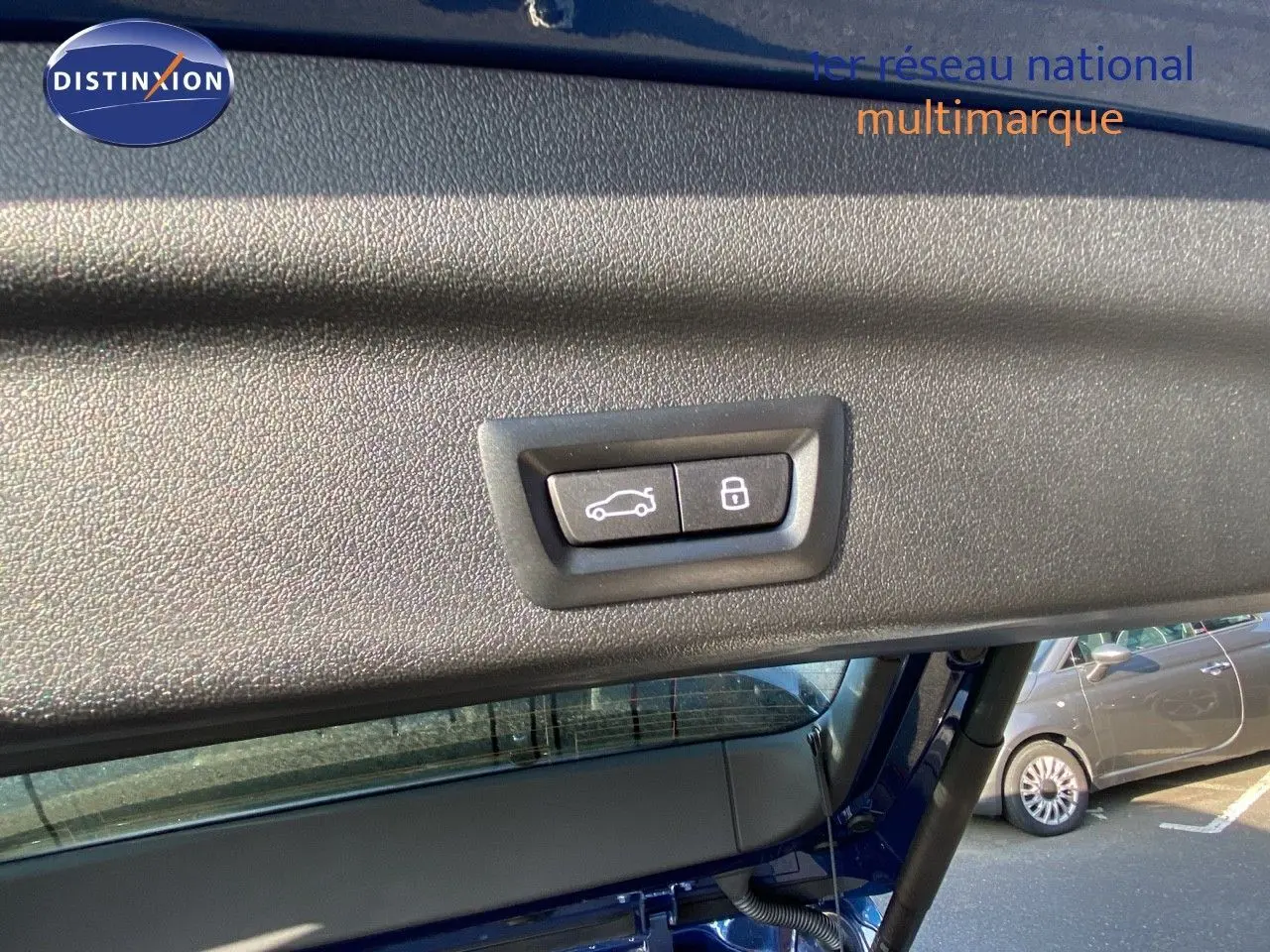 Boutons de fermeture et verrouillage du hayon sur le coffre d'un BMW X1 bleu phytonic metal, vue intérieure arrière.