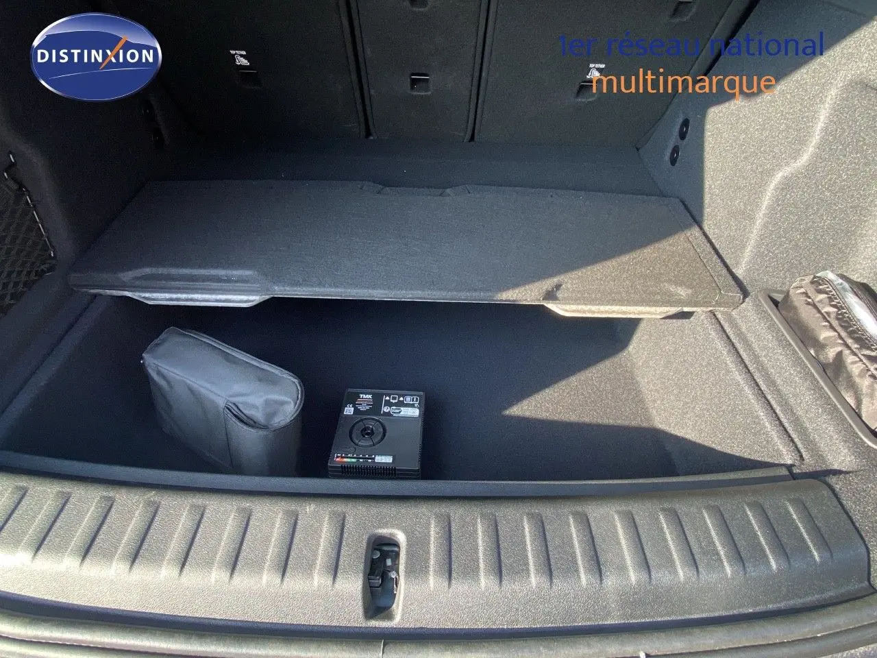 Coffre ouvert du BMW X1 18I bleu Phytonic Metal, montrant le rangement sous plancher avec kit de réparation pneus.