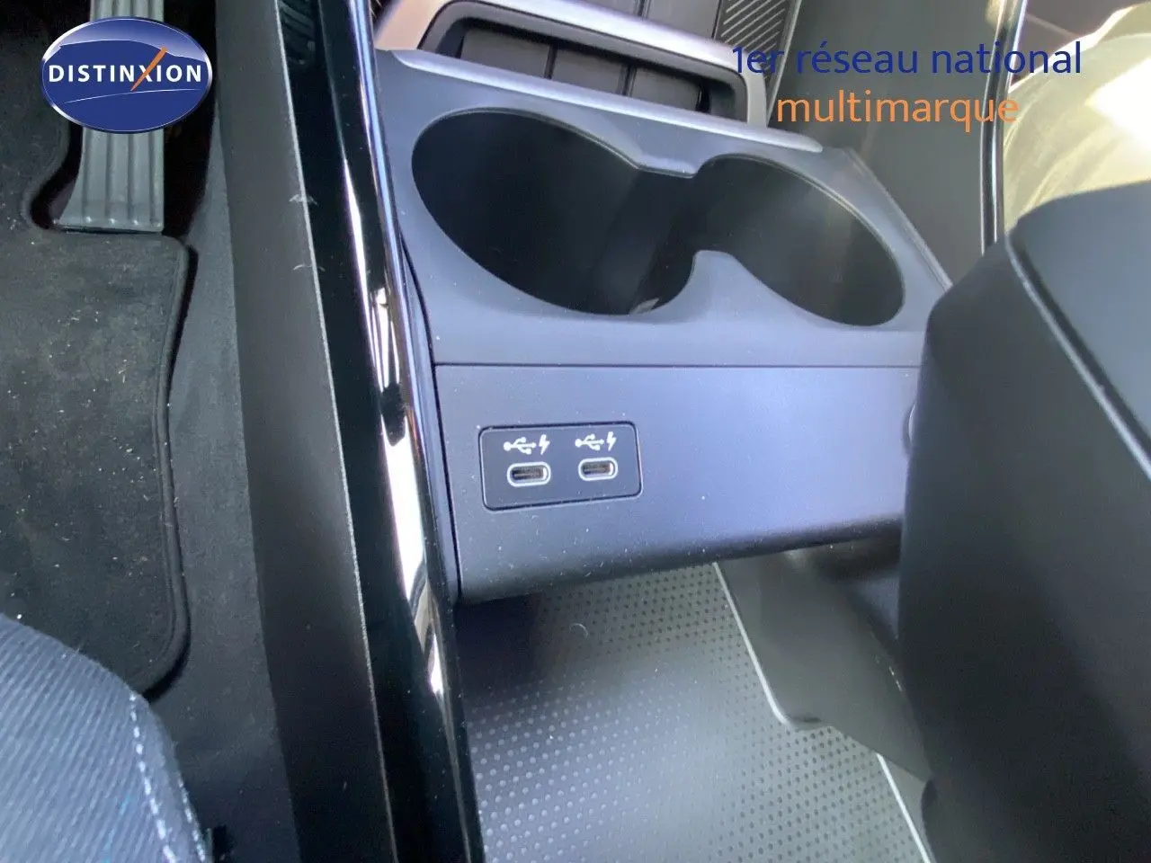 Gros plan sur la console centrale du BMW X1 18I bleu Phytonic, montrant deux ports USB-C et porte-gobelets.