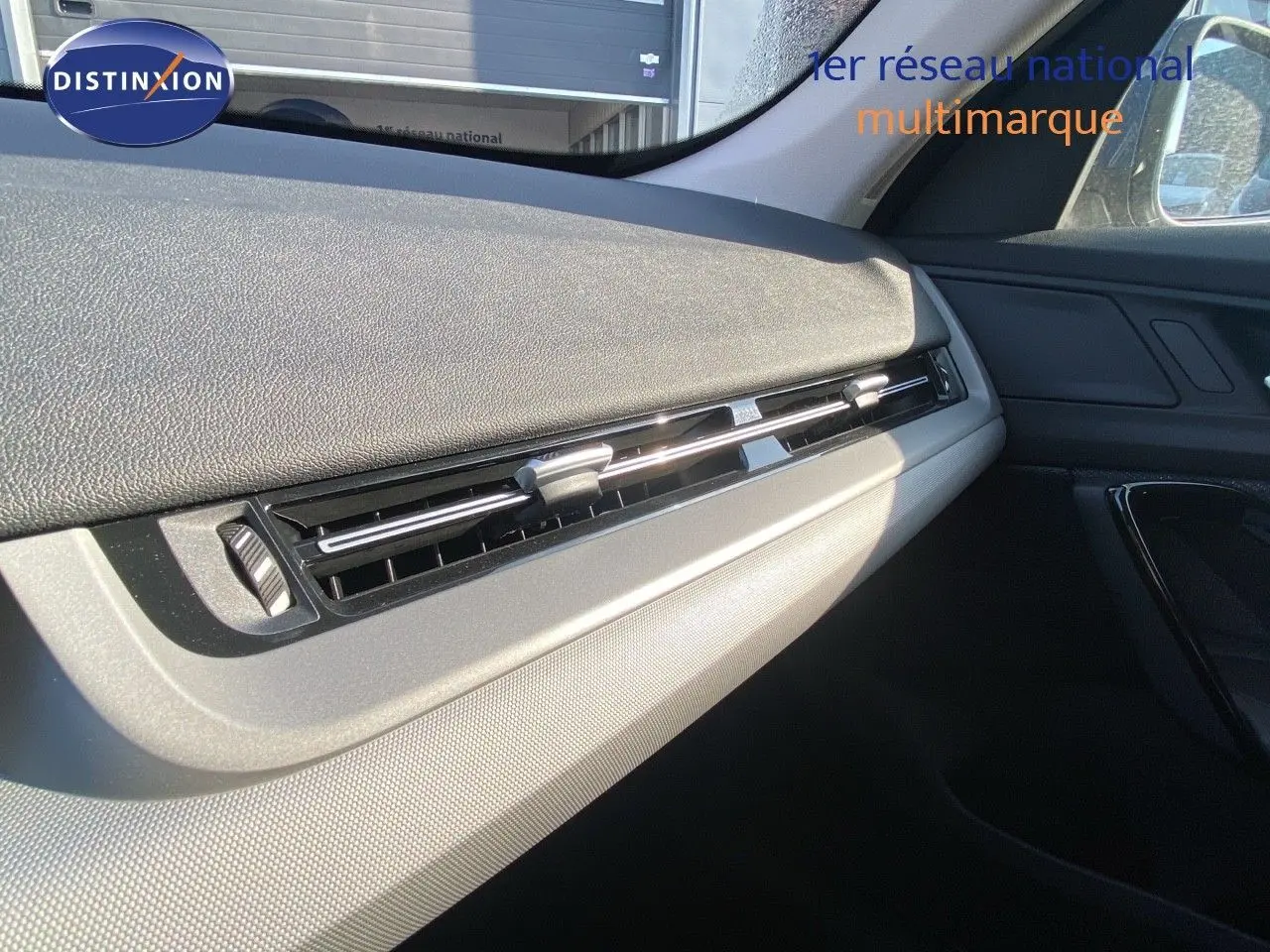 Détail de la partie droite du tableau de bord du BMW X1 18I 136CH bleu Phytonic Metal, avec aérateurs horizontaux.