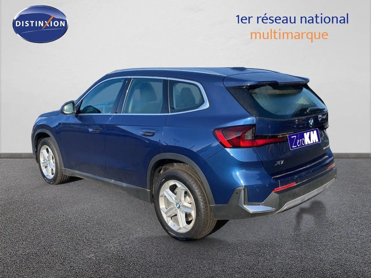 BMW X1 18I bleu Phytonic metal vu de l'arrière côté gauche, mettant en valeur ses feux LED et ses jantes argentées.