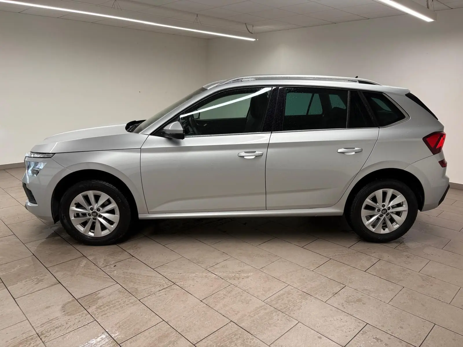 Vue latérale droite d'un Skoda Kamiq gris argent 2025 avec peinture métallisée et caméra de recul visible sur le hayon.