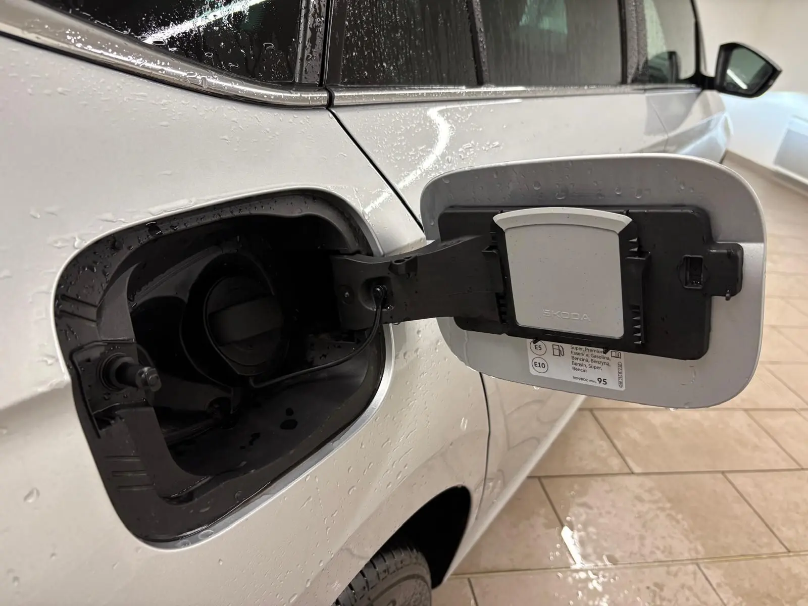 Vue rapprochée de la trappe à carburant ouverte côté gauche d’un Skoda Kamiq gris argent 2025.