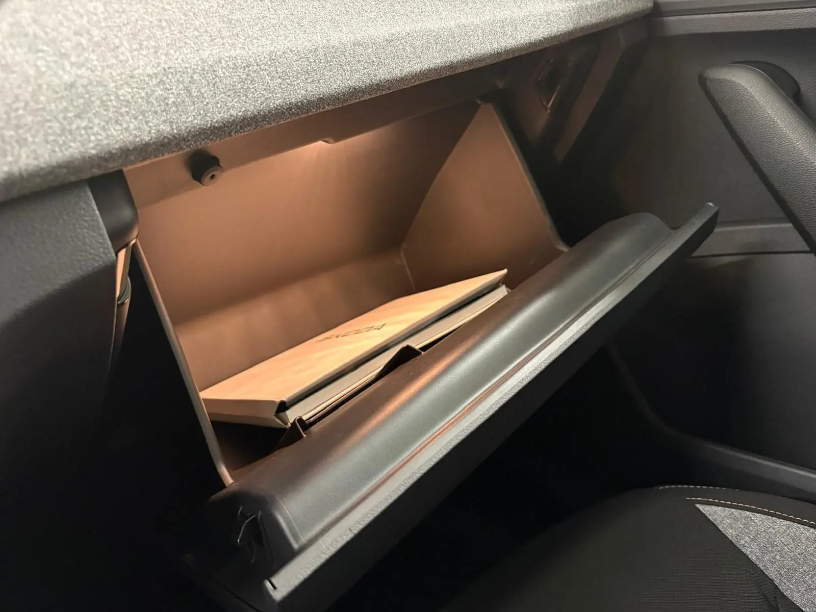 Gant de boîte à gants ouvert dans l'habitacle du Skoda Kamiq 2025, avec manuel visible à l'intérieur.