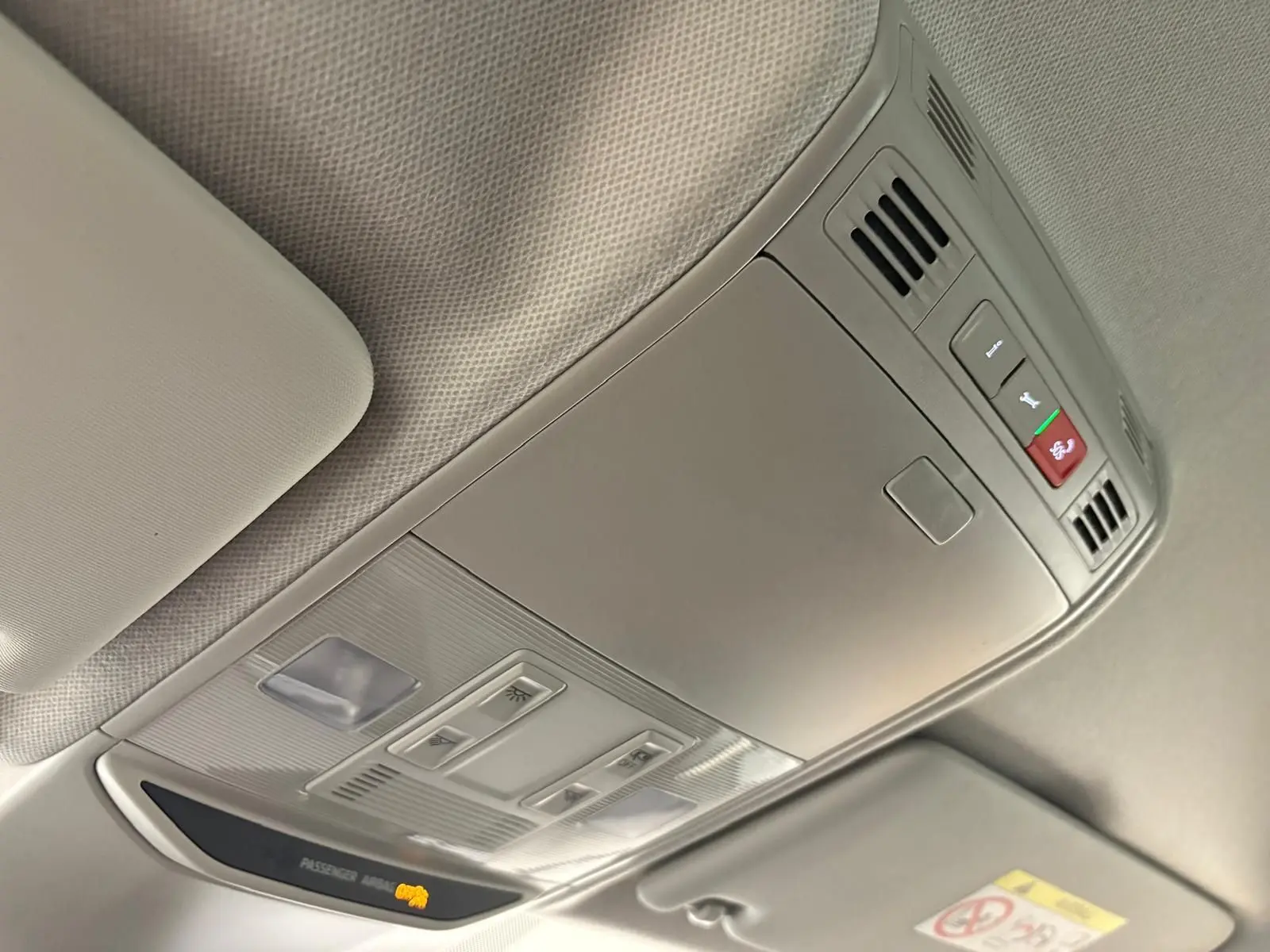 Vue intérieure du plafonnier gris clair avec commandes d'éclairage et indicateur airbag passager actif.