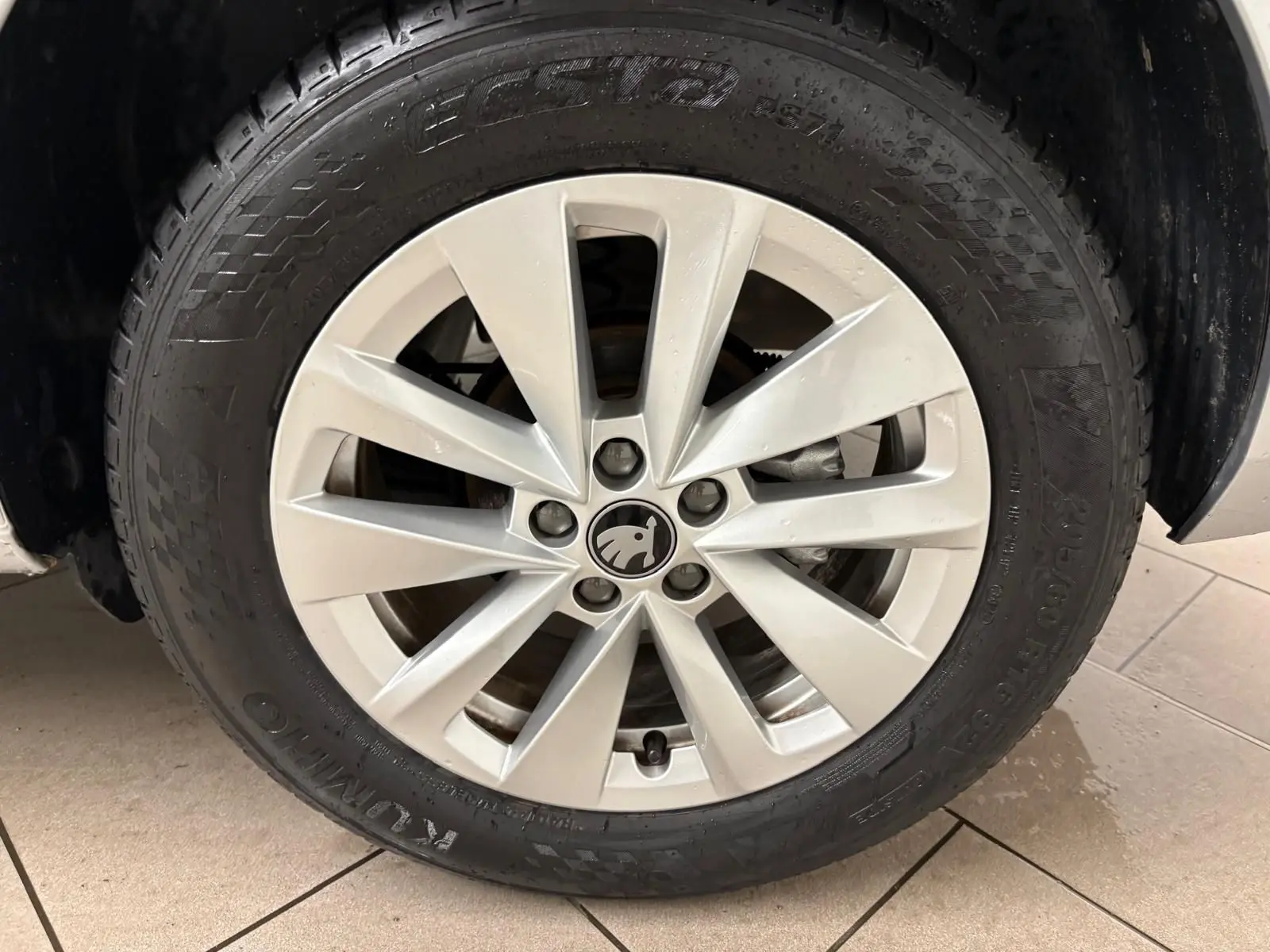 Gros plan sur la roue avant gauche avec jante argentée et logo ŠKODA au centre du SUV gris argent 2025.