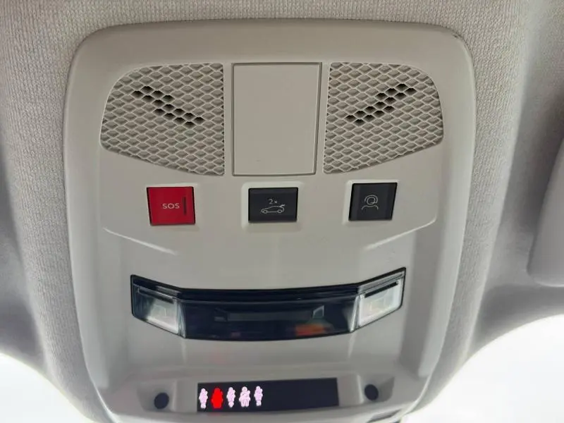 Vue en contre-plongée du panneau de commandes au plafond intérieur de la FIAT 600 noire, avec bouton SOS rouge et éclairage intégré.