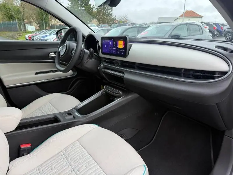Vue intérieure côté conducteur de la FIAT 600 2024 hybride, avec tableau de bord clair et écran tactile central.
