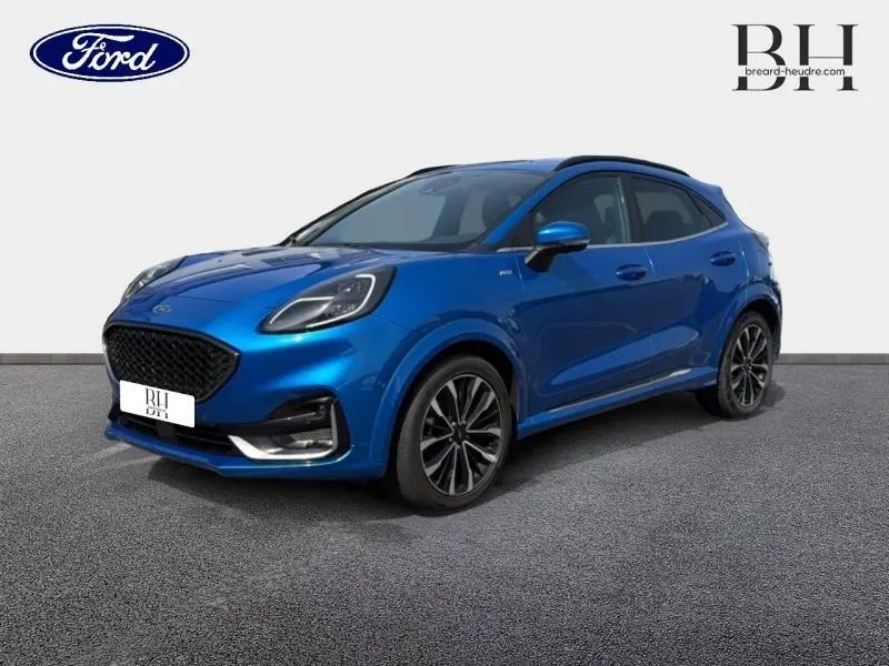 Ford Puma 1.0 EcoBoost bleu métallisé en 3/4 avant droit avec jantes alu noires et barres de toit noires.