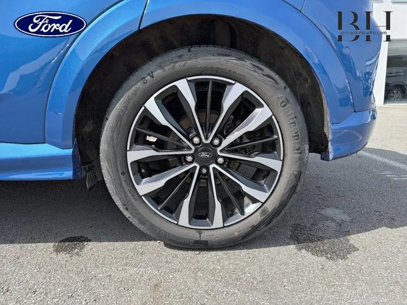 Gros plan sur la roue avant droite avec jante alu bicolore du Ford Puma bleu Fashion Island métallisé.