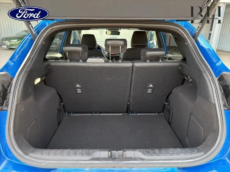 Coffre ouvert vu de l'arrière d'un Ford Puma bleu Fashion avec banquette arrière en tissu noir et hayon électrique.