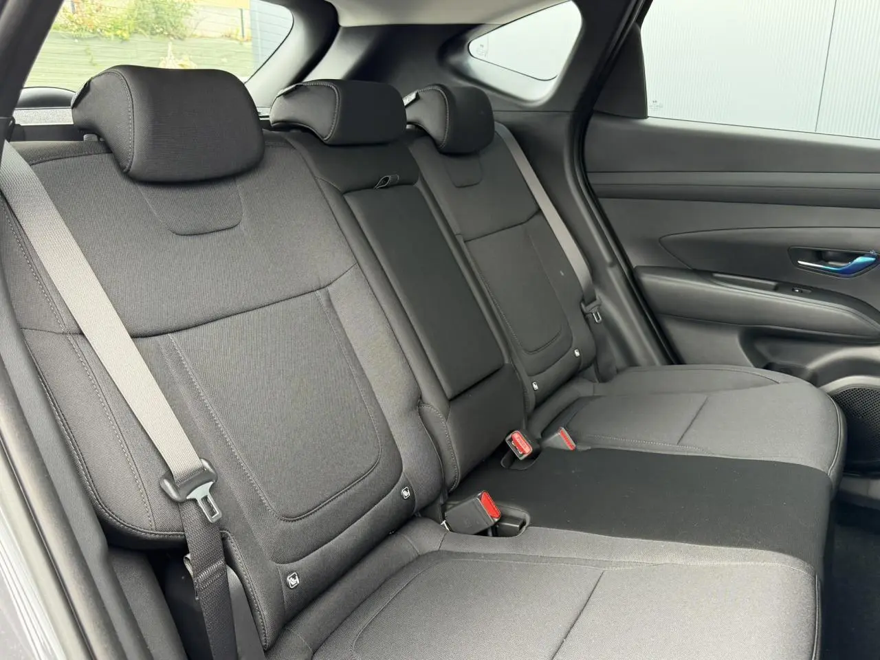 Vue intérieure côté droit des sièges arrière gris foncé du Hyundai Tucson 2026 avec ceintures et appuie-têtes visibles.