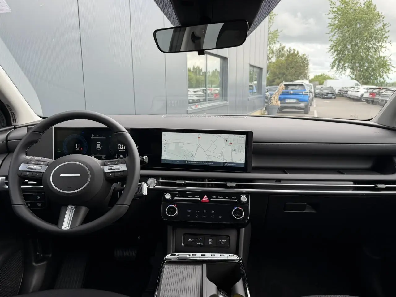 Vue intérieure avant du Hyundai Tucson 2026 avec tableau de bord noir et écran tactile central large affichant la navigation.