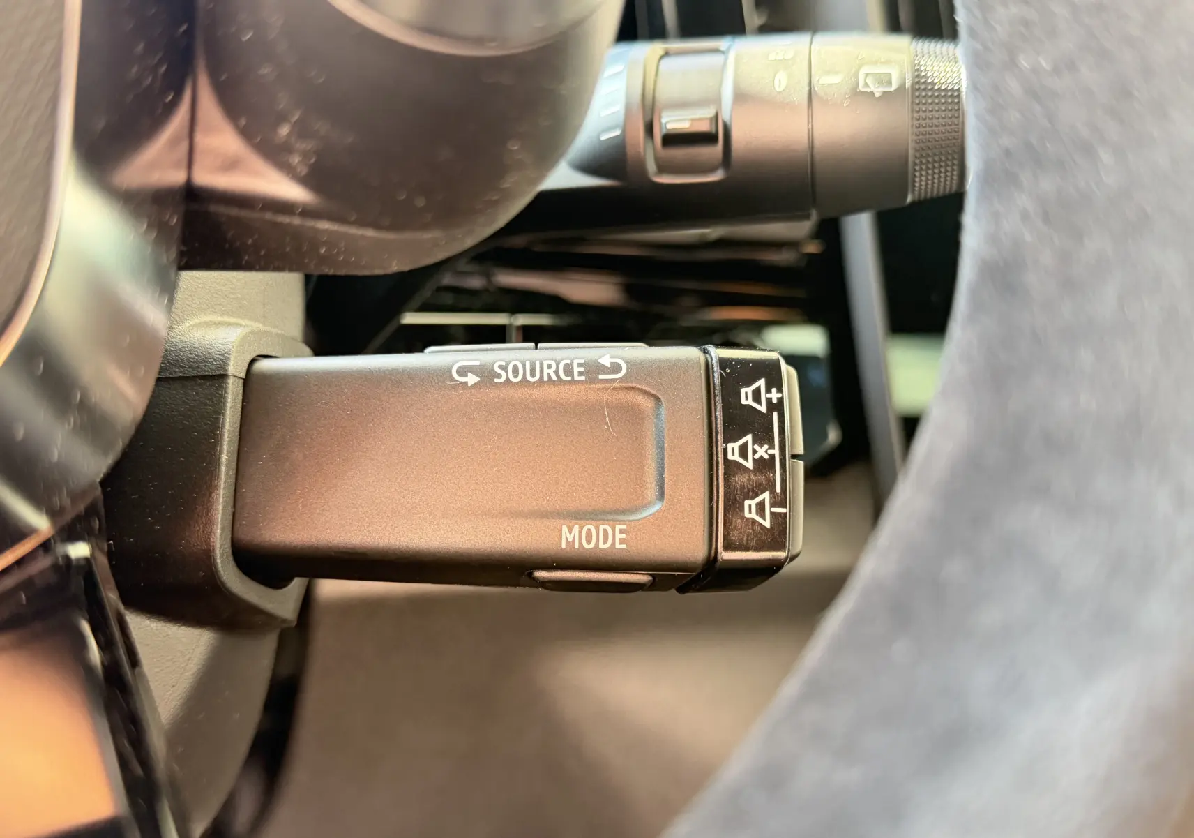 Gros plan sur la commande au volant du Renault Austral E-Tech 200 Esprit Alpine, avec boutons source et mode visibles.