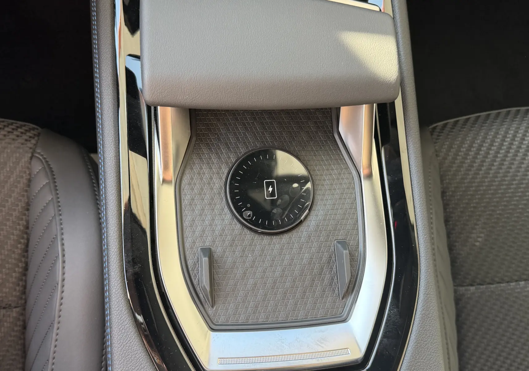 Vue rapprochée du chargeur sans fil au centre de la console d’un Renault Austral E-Tech 200 Esprit Alpine, intérieur gris.