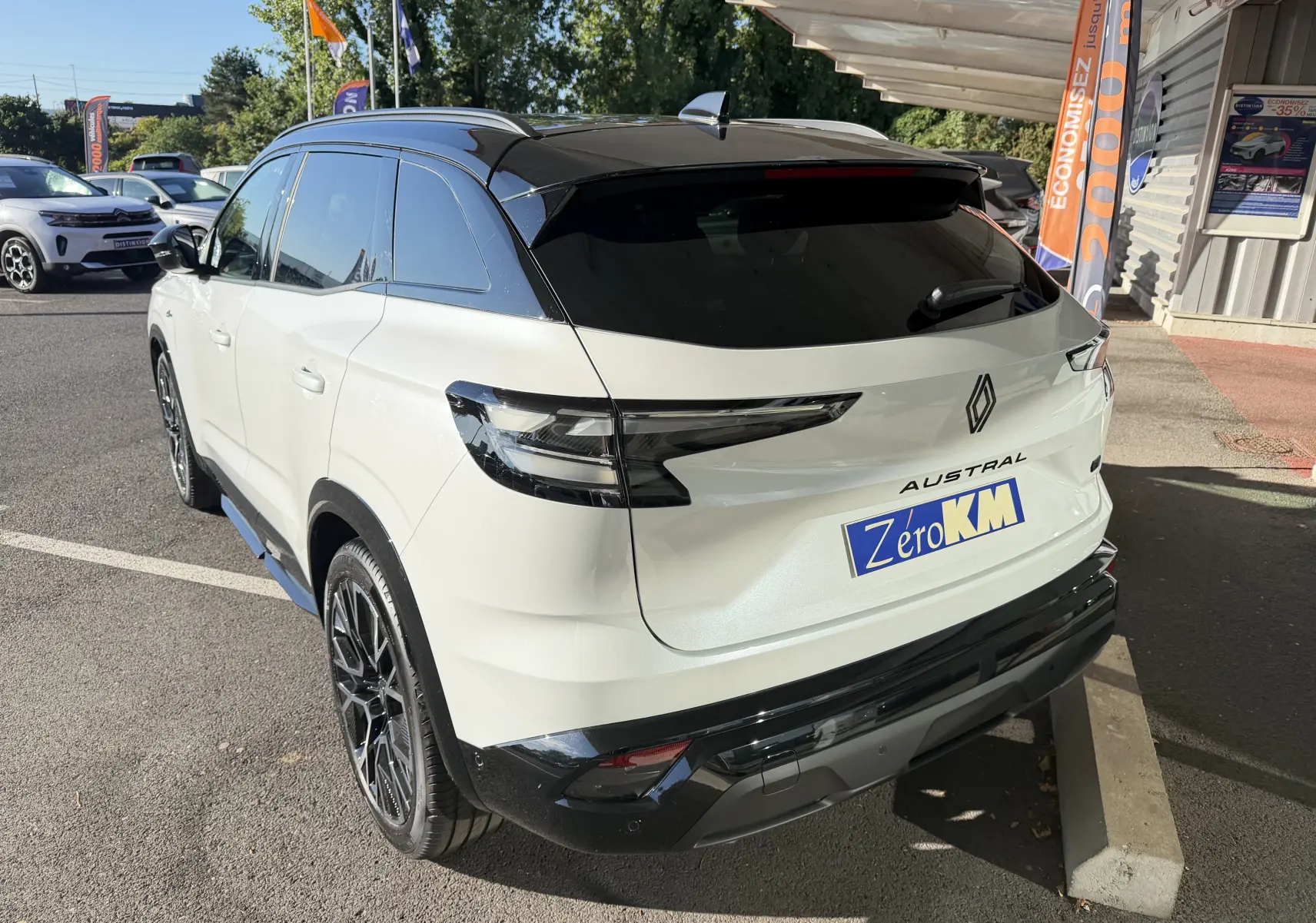 Vue 3/4 arrière d’un Renault Austral E-Tech blanc nacré avec toit noir, jantes 20 pouces et feux arrière LED distinctifs.