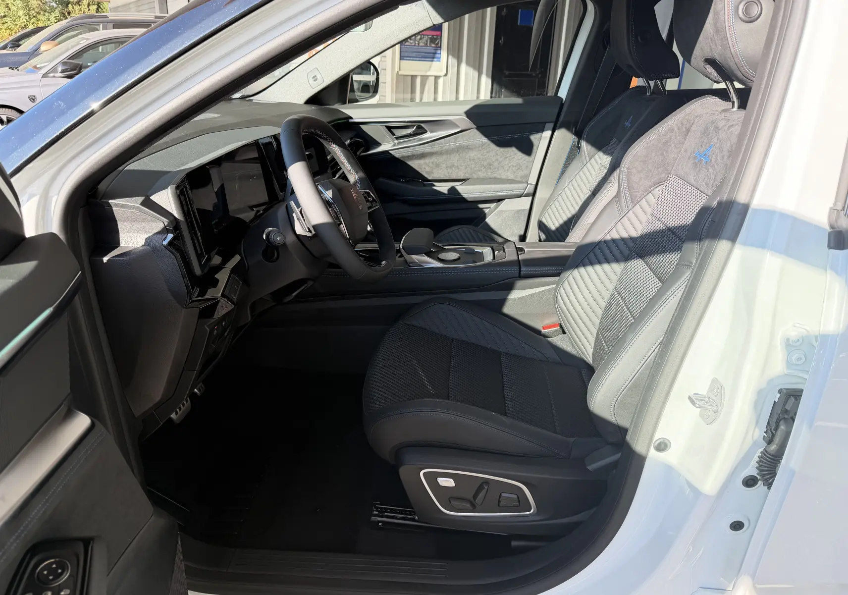 Vue intérieure côté conducteur du Renault Austral E-Tech 200 Esprit Alpine blanc nacré, sièges en Alcantara avec logo Alpine brodé.