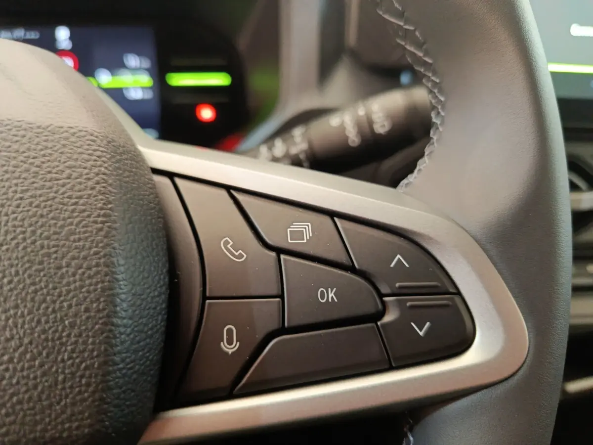 Gros plan sur les commandes multifonctions à droite du volant cuir du Dacia Duster Journey Hybrid 155 noir 2026.