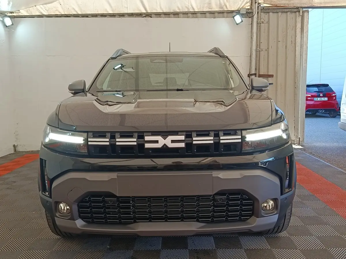 Vue de face du Dacia Duster Journey Hybrid 155 noir avec calandre distinctive et feux LED allumés.