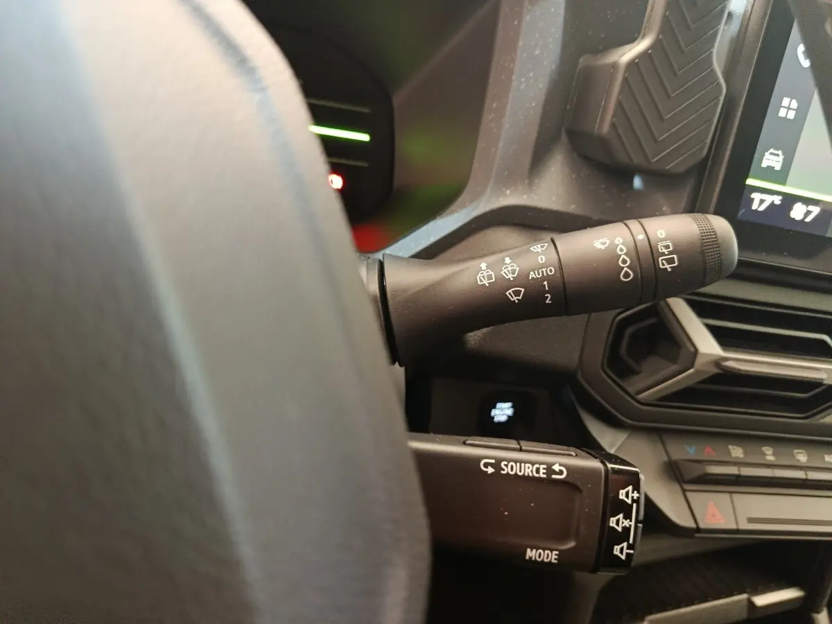 Gros plan sur les commandes au volant et la manette d’essuie-glace du tableau de bord du Dacia Duster noir hybride 2026.