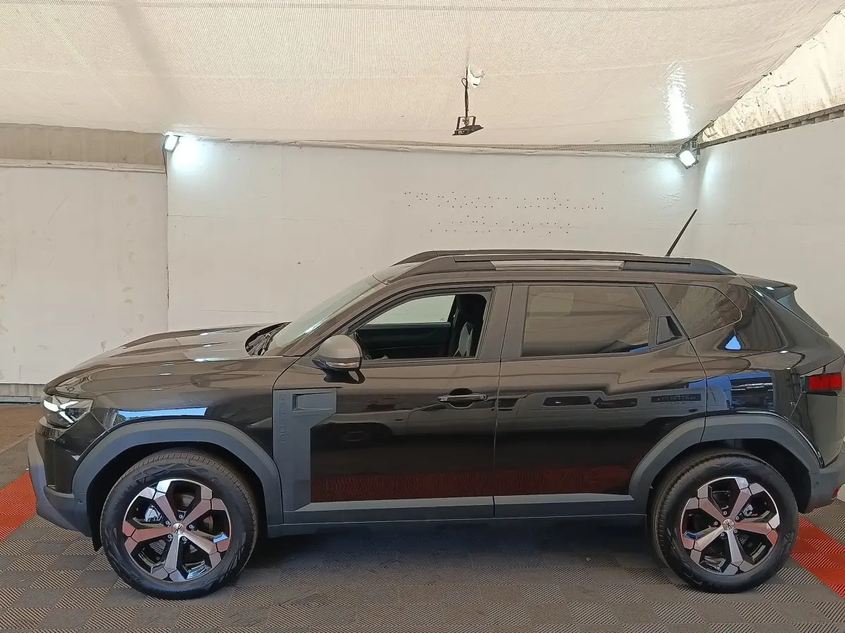 Vue de profil côté gauche du Dacia Duster Journey Hybrid 155 noir, avec jantes alliage et barres de toit noires.