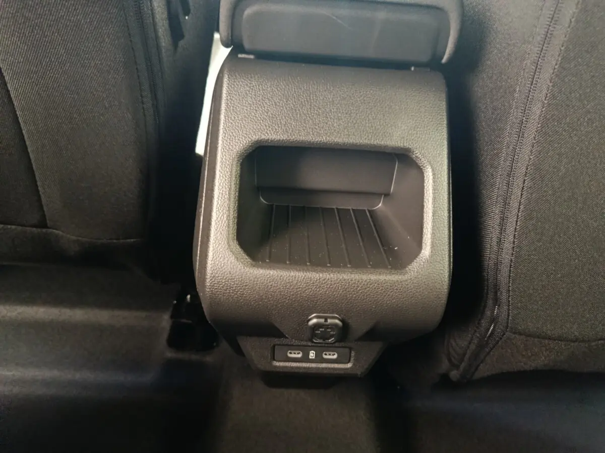 Vue rapprochée de la console arrière noire du Dacia Duster Journey Hybrid 155 avec ports USB et prise 12V.