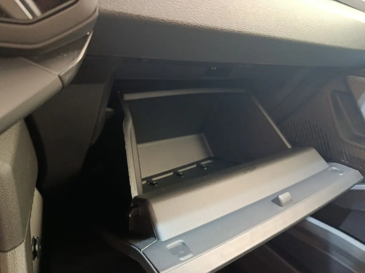 Vue rapprochée de la boîte à gants ouverte côté passager dans l’habitacle noir du Dacia Duster Journey Hybrid 2026.