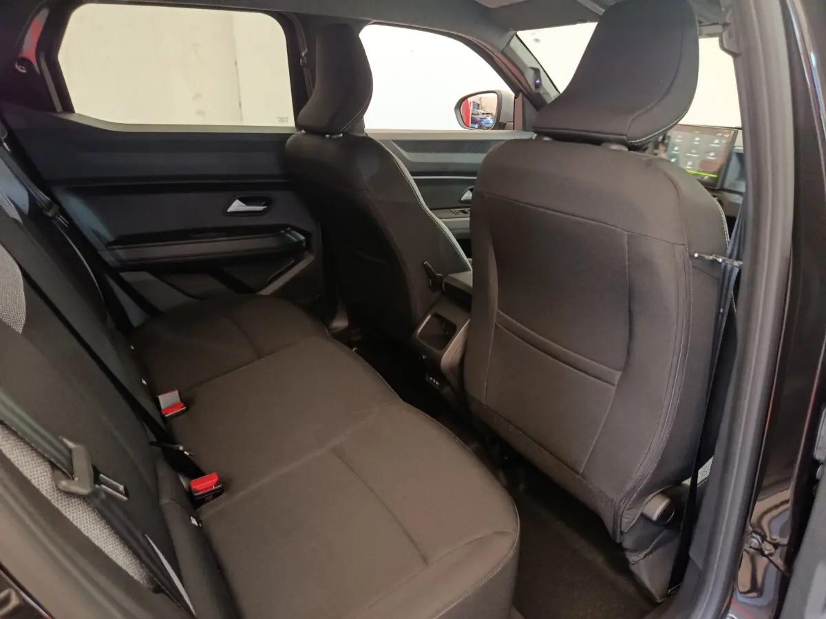 Vue intérieure côté arrière droit du Dacia Duster Journey Hybrid 155 noir, montrant les sièges arrière et la console centrale.