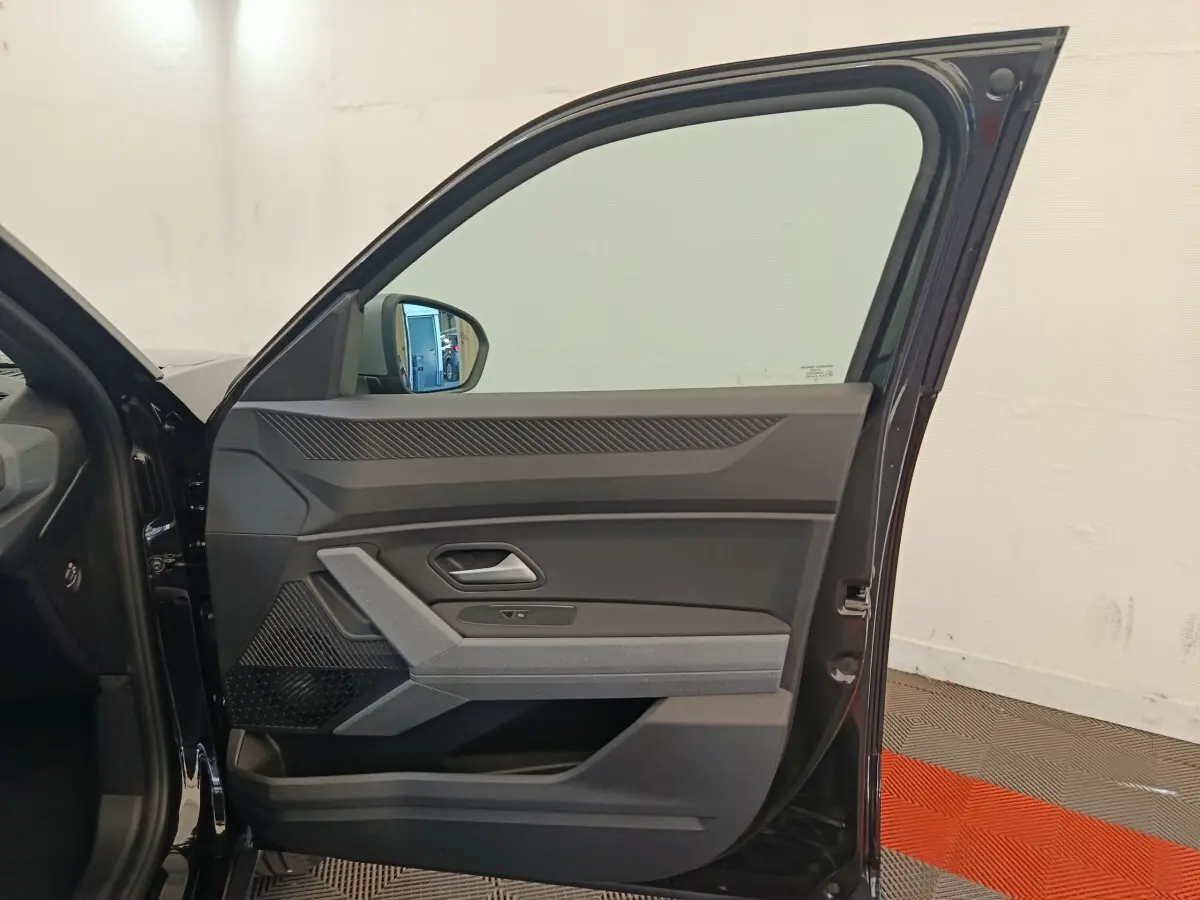 Vue intérieure de la porte avant gauche noire du Dacia Duster Journey Hybrid 155, avec détails des commandes et poignée intégrée.