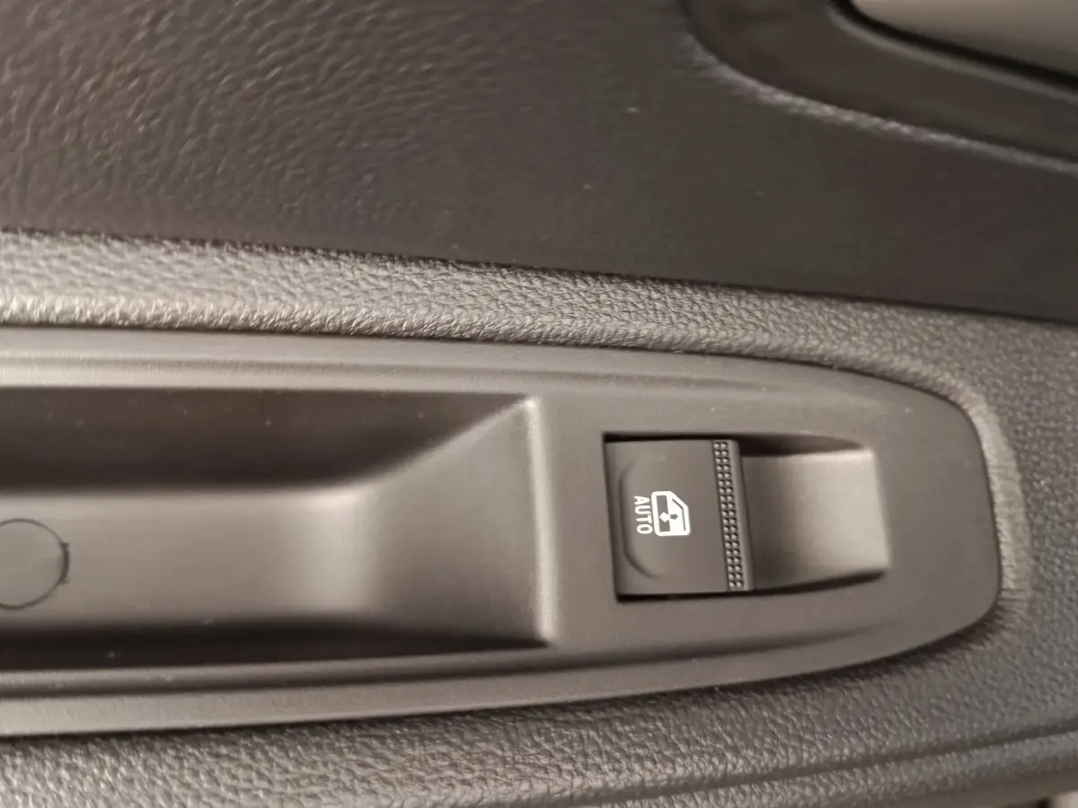 Gros plan sur le bouton de commande de la vitre électrique automatique côté conducteur du Dacia Duster noir 2026.