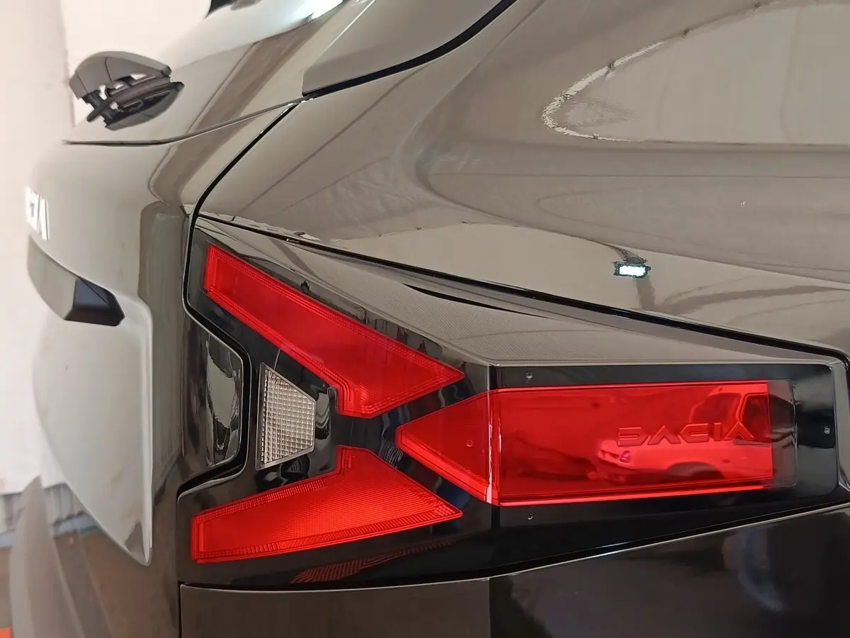Gros plan sur le feu arrière droit rouge et blanc d'un Dacia Duster Journey Hybrid 155 noir, finition 2026.