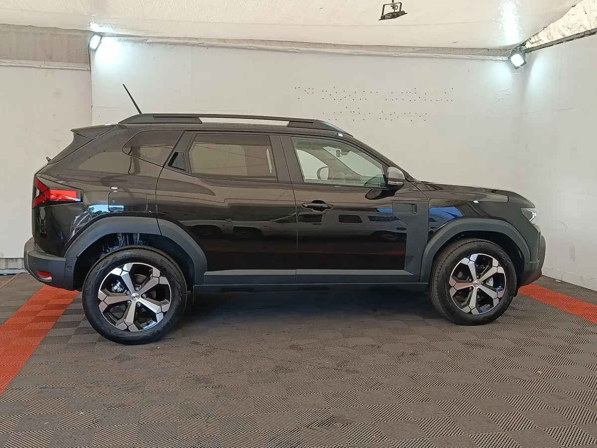 Vue de profil côté gauche du Dacia Duster Journey Hybrid 155 noir, avec jantes alliage et barres de toit noires.