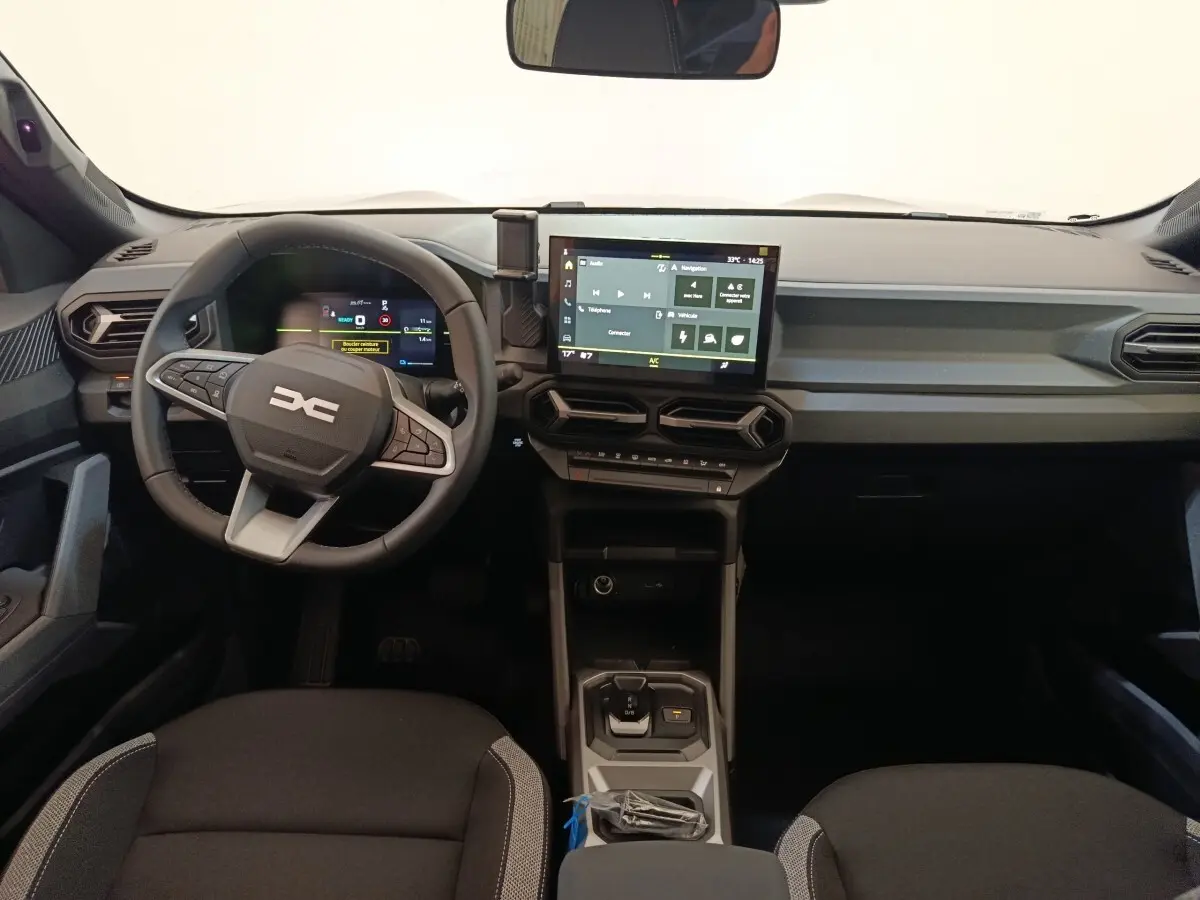 Vue intérieure avant du tableau de bord du Dacia Duster Journey Hybrid 155 avec écran tactile central et volant multifonctions.