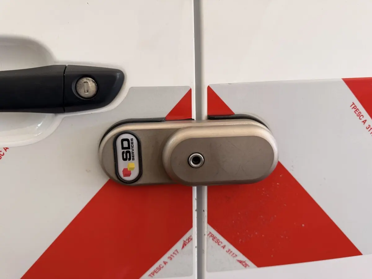 Gros plan sur la serrure arrière gauche d’un Citroën Berlingo blanc 2019 avec marquages rouges et dispositif de sécurité SD Services.