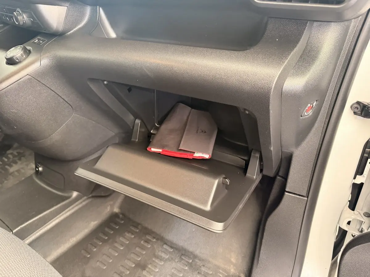 Gant de boîte à gants ouvert côté passager dans un Citroën Berlingo blanc 2019, avec un carnet de bord visible.
