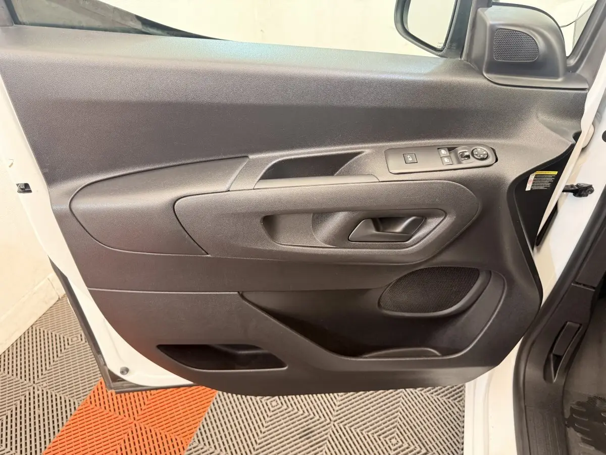 Vue rapprochée de la porte avant gauche noire du Citroën Berlingo blanc, avec commandes de vitres et rétroviseur.