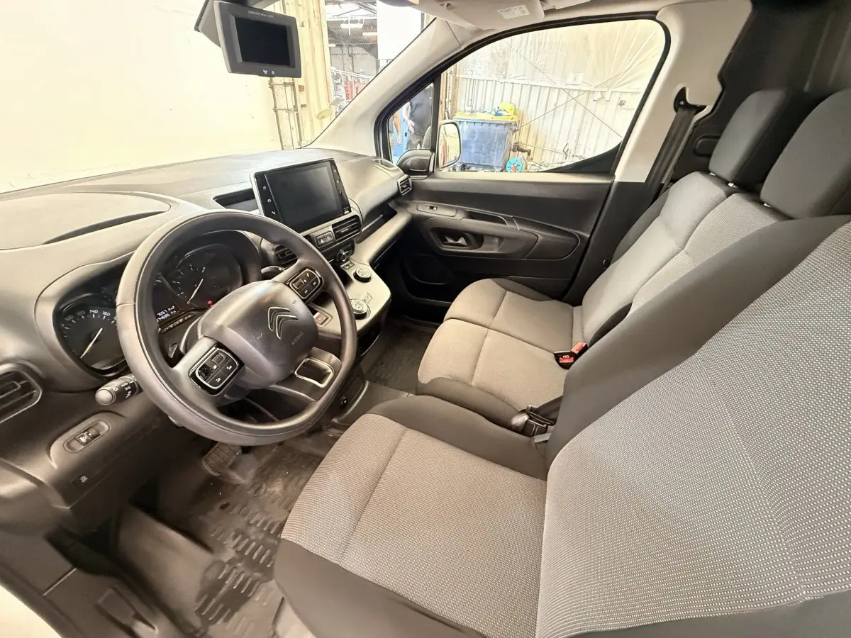 Vue intérieure côté conducteur du Citroën Berlingo 2019 avec tableau de bord noir et sièges tissu gris.
