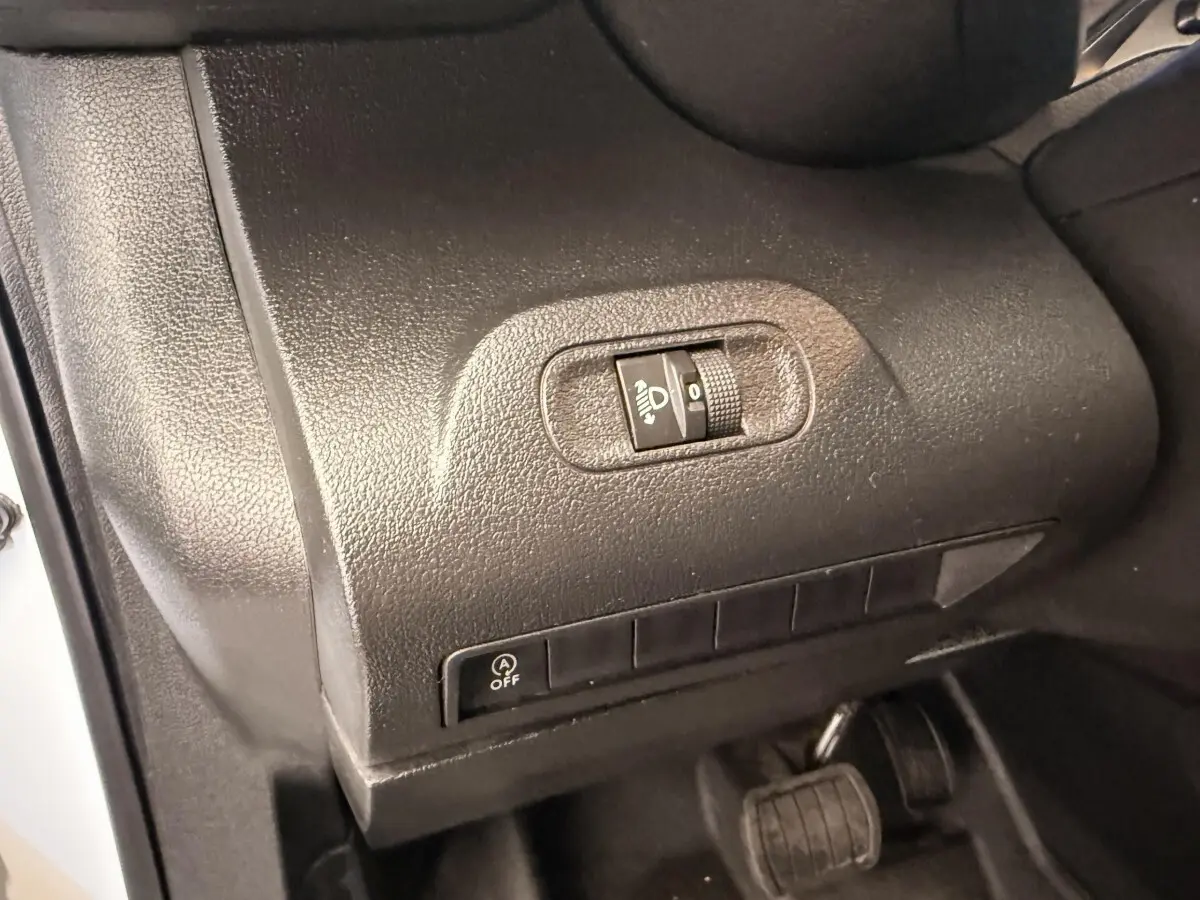 Détail intérieur côté gauche du tableau de bord du Citroën Berlingo blanc 2019, avec commande de réglage des phares.